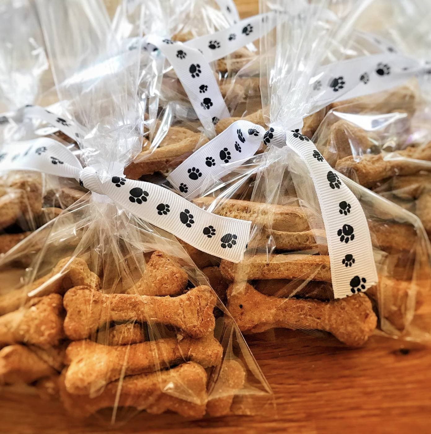 Homemade bone-shaped dog biscuits bagged in cellophane tied with paw-print ribbons